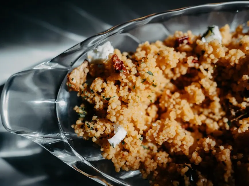 Grains de couscous humectés dans un saladier, eau salée versée avant cuisson vapeur